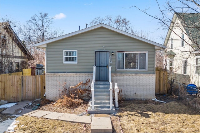 bungalow-style house featuring brick siding and fence