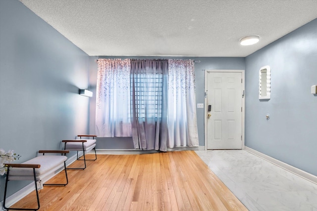 foyer with baseboards, marble finish floor, and a textured ceiling