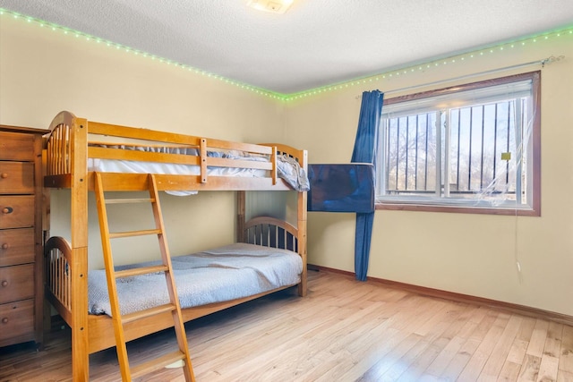 bedroom featuring a textured ceiling, baseboards, and wood finished floors