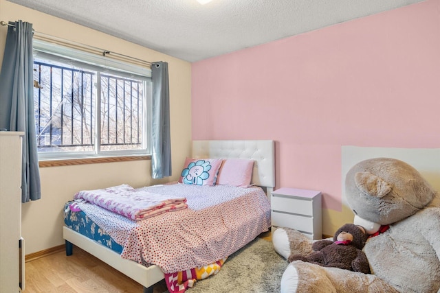 bedroom with baseboards, a textured ceiling, and wood finished floors