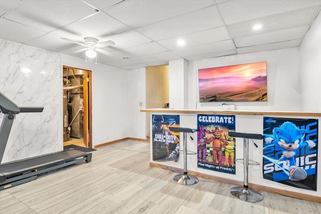 workout area with wood finished floors, baseboards, a drop ceiling, and ceiling fan