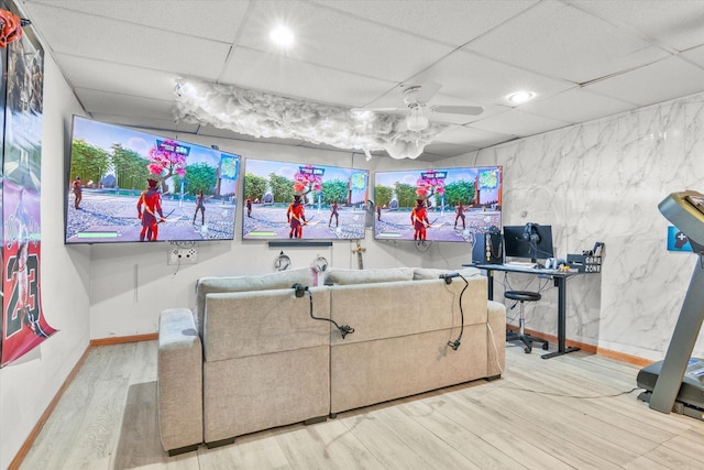 interior space featuring a ceiling fan, wood finished floors, baseboards, and a drop ceiling