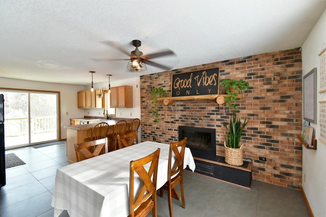 dining space featuring a fireplace, a textured ceiling, brick wall, and light tile patterned floors