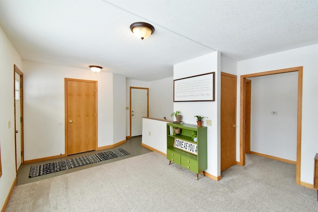 entrance foyer featuring a textured ceiling, baseboards, and carpet flooring