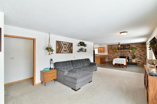 living room with a fireplace, light colored carpet, a textured ceiling, brick wall, and baseboards