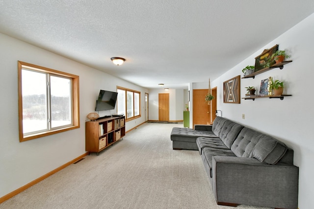 living area with visible vents, baseboards, a textured ceiling, and light colored carpet