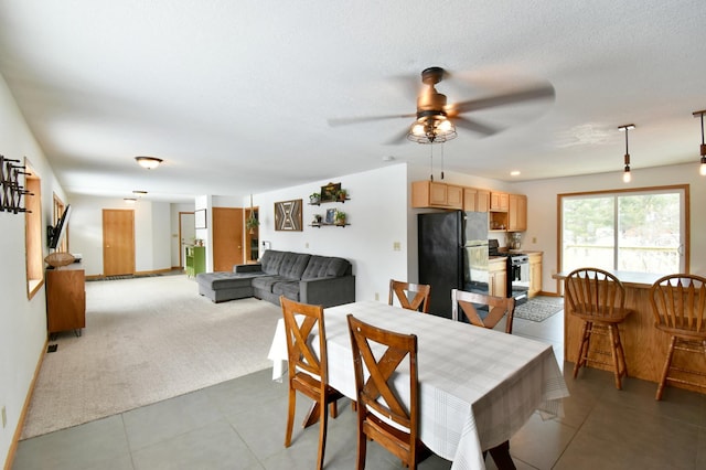 dining space featuring a ceiling fan, a textured ceiling, baseboards, and light tile patterned floors