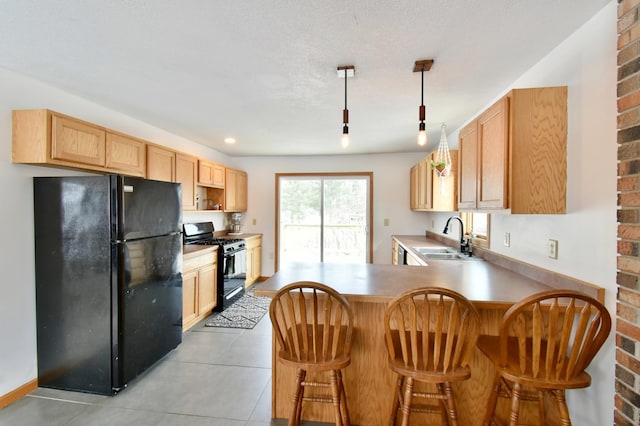 kitchen with a peninsula, a sink, hanging light fixtures, light countertops, and black appliances