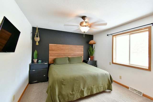 bedroom featuring a ceiling fan, light colored carpet, visible vents, and baseboards