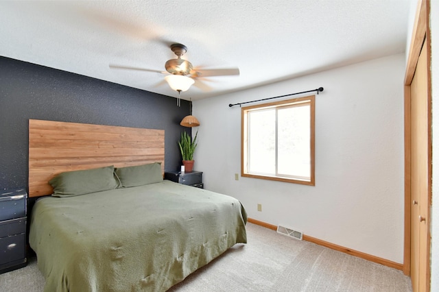 bedroom featuring a ceiling fan, visible vents, light carpet, and baseboards