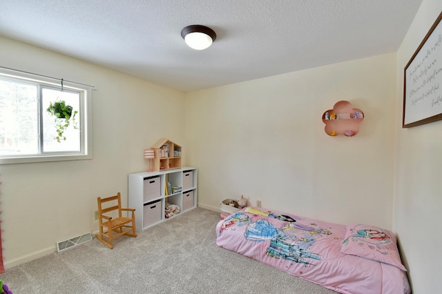 bedroom featuring a textured ceiling, baseboards, visible vents, and light colored carpet