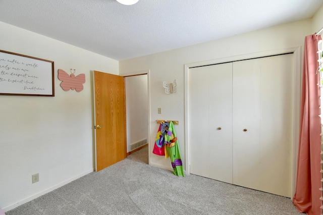 bedroom featuring a textured ceiling, a closet, and light colored carpet