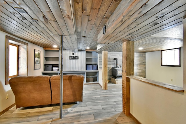 interior space featuring light wood finished floors, built in features, wood ceiling, a wood stove, and recessed lighting