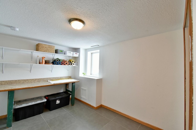 office area featuring a textured ceiling, baseboards, and light tile patterned floors