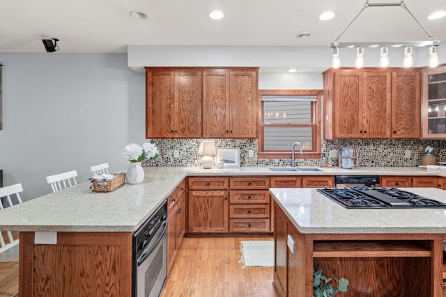 kitchen with sink, light hardwood / wood-style flooring, a breakfast bar area, appliances with stainless steel finishes, and tasteful backsplash