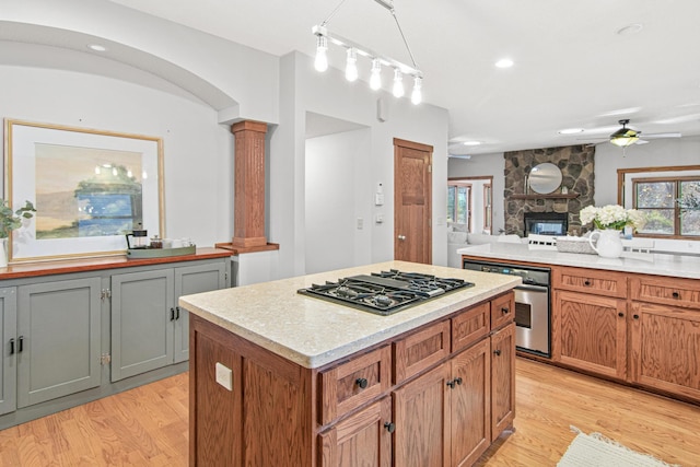 kitchen with a center island, black gas stovetop, light hardwood / wood-style flooring, and ornate columns