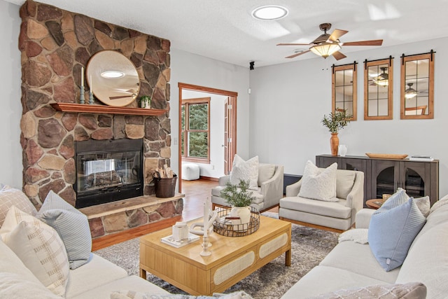 living room featuring ceiling fan, hardwood / wood-style floors, a textured ceiling, and a fireplace