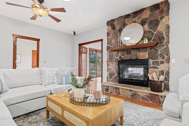 living room featuring hardwood / wood-style flooring, ceiling fan, a fireplace, and a textured ceiling