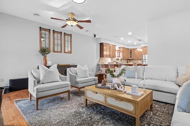 living room featuring ceiling fan, dark hardwood / wood-style floors, and a textured ceiling