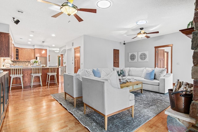 living room featuring a textured ceiling, light hardwood / wood-style flooring, and ceiling fan