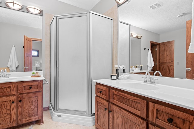 bathroom with an enclosed shower, vanity, tile patterned floors, and a textured ceiling