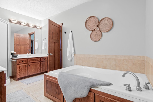 bathroom featuring vanity, tile patterned floors, a bathing tub, and a textured ceiling