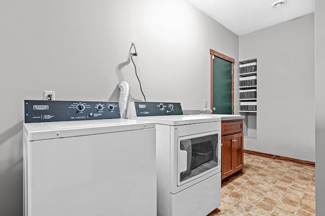 laundry room with cabinets, washer and clothes dryer, and a textured ceiling