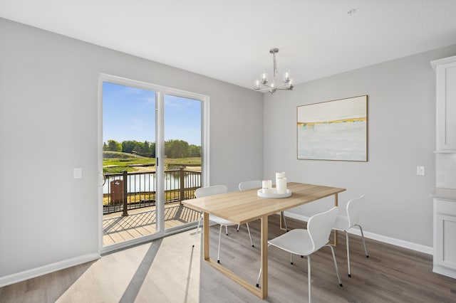 dining area with a water view, a notable chandelier, and hardwood / wood-style flooring