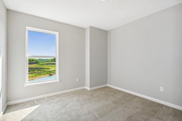 empty room featuring baseboards, visible vents, and light colored carpet