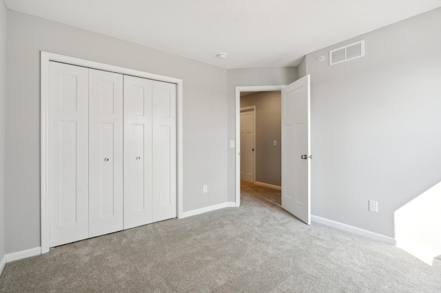 unfurnished bedroom featuring light carpet, a closet, visible vents, and baseboards