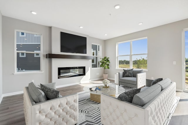 living room with baseboards, wood finished floors, a glass covered fireplace, and recessed lighting