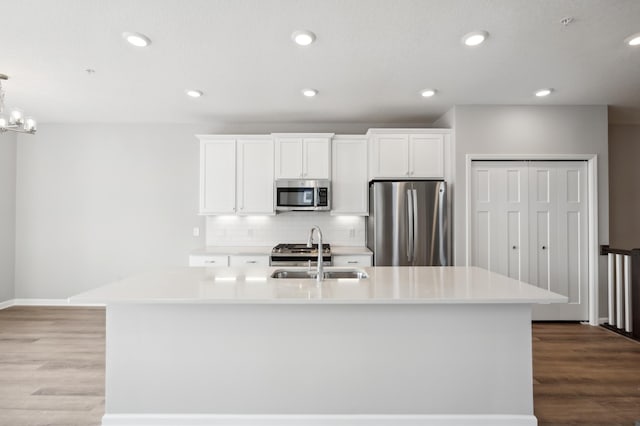 kitchen featuring a center island with sink, light countertops, appliances with stainless steel finishes, white cabinetry, and a sink