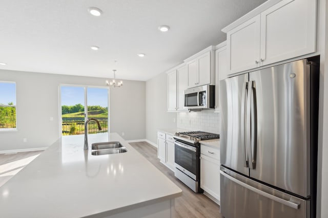 kitchen with stainless steel appliances, tasteful backsplash, light countertops, white cabinetry, and a sink