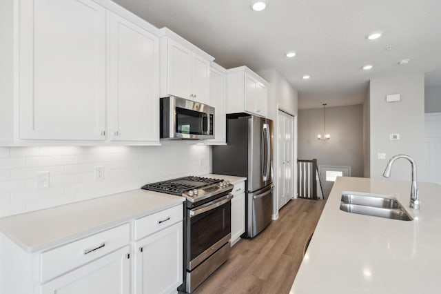 kitchen with decorative backsplash, stainless steel appliances, light countertops, white cabinetry, and a sink