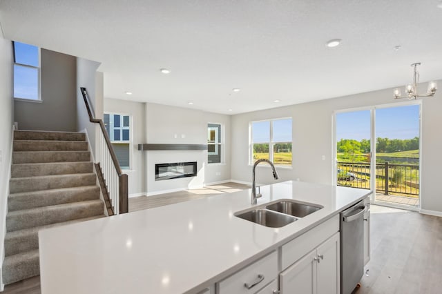 kitchen featuring a sink, white cabinets, light countertops, dishwasher, and decorative light fixtures