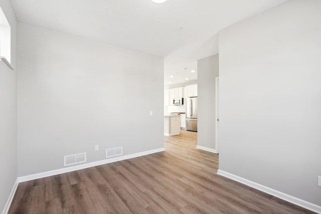 spare room with baseboards, visible vents, and light wood-style floors