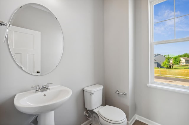 half bathroom featuring baseboards, a sink, and toilet