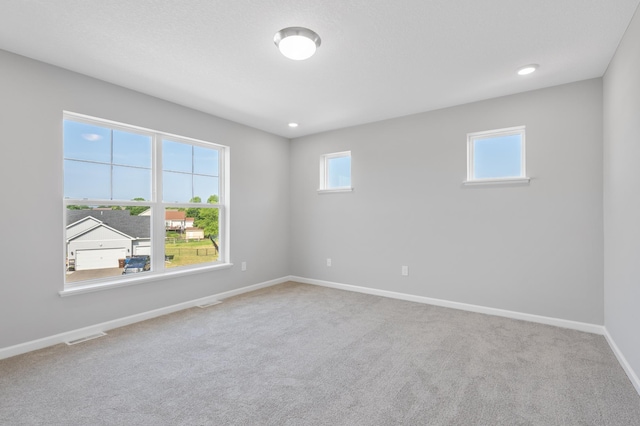 spare room featuring recessed lighting, carpet flooring, visible vents, and baseboards