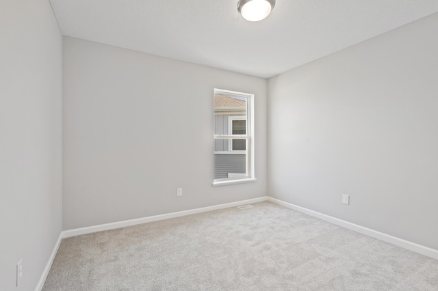 spare room with light colored carpet and baseboards