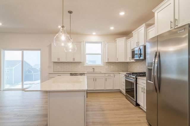 kitchen featuring a kitchen island, pendant lighting, tasteful backsplash, white cabinets, and stainless steel appliances