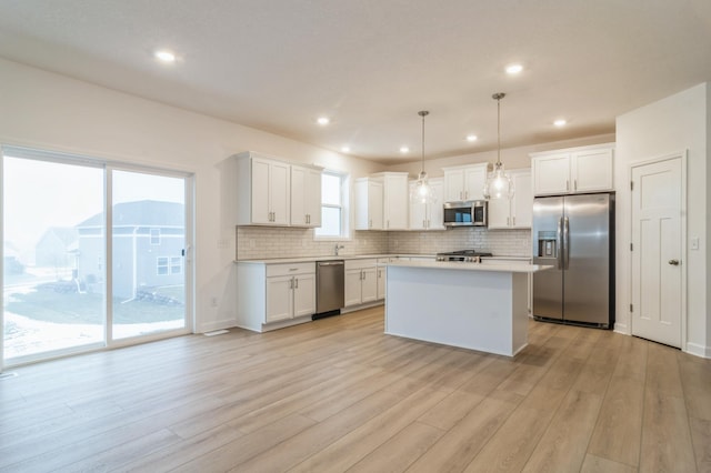 kitchen with white cabinetry, stainless steel appliances, and hanging light fixtures