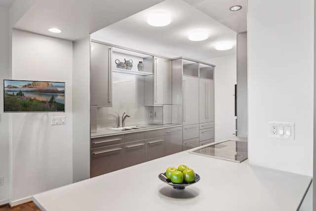 kitchen with gray cabinets, sink, black electric cooktop, and kitchen peninsula