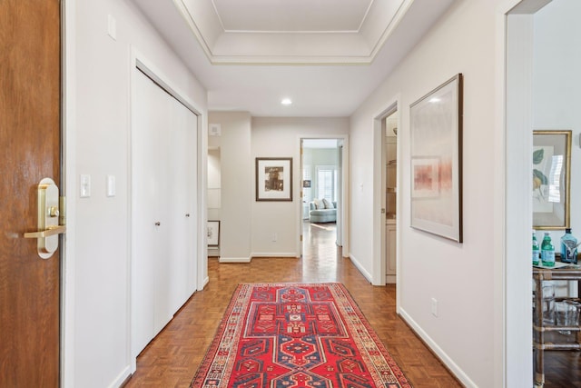 hall featuring a tray ceiling and parquet flooring