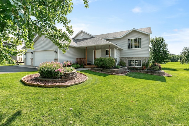 view of front of home featuring covered porch, driveway, a front lawn, and an attached garage