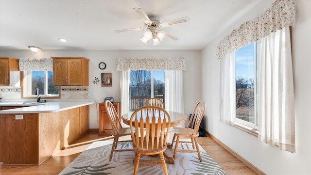 dining area with light wood-style floors, baseboards, and a ceiling fan