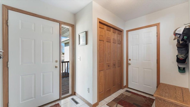 entrance foyer featuring visible vents, a textured ceiling, baseboards, and light tile patterned floors