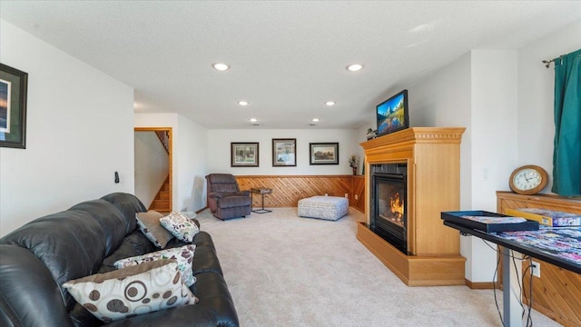 living room featuring a textured ceiling, recessed lighting, light carpet, stairway, and a glass covered fireplace