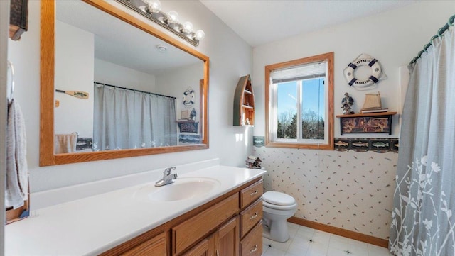 bathroom with wallpapered walls, toilet, vanity, baseboards, and tile patterned floors