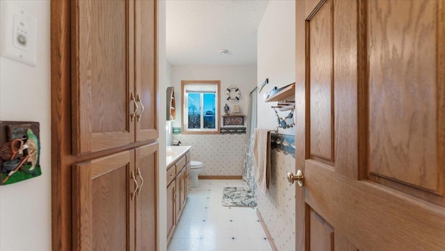 full bathroom featuring toilet, vanity, a shower, tile patterned floors, and wallpapered walls