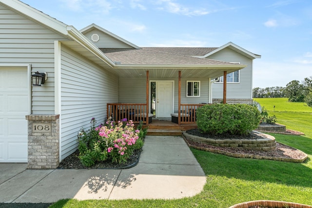 doorway to property featuring a garage, covered porch, a shingled roof, and a yard